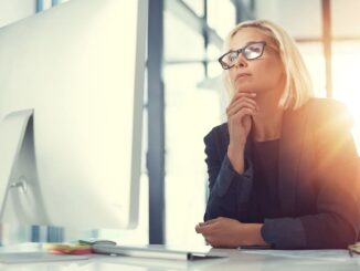 Mulher pensativa diante do computador refletindo sobre como saber se é intuição ou mente
